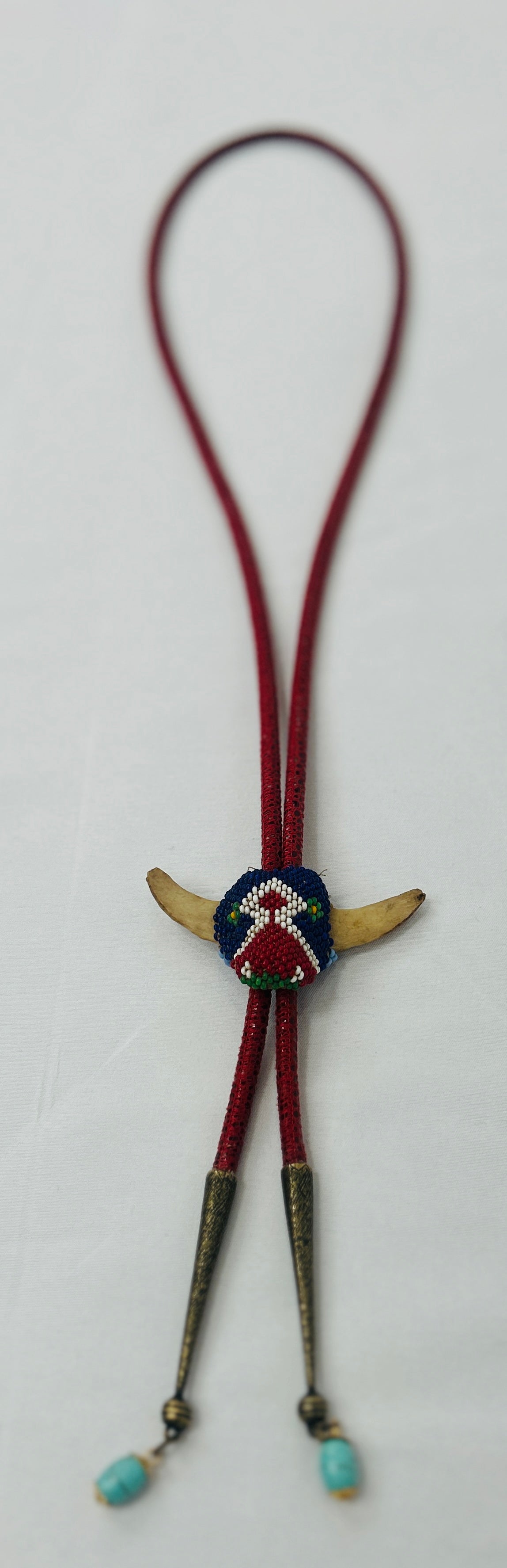 Bolo tie with decorative center and turquoise beads on a white background
